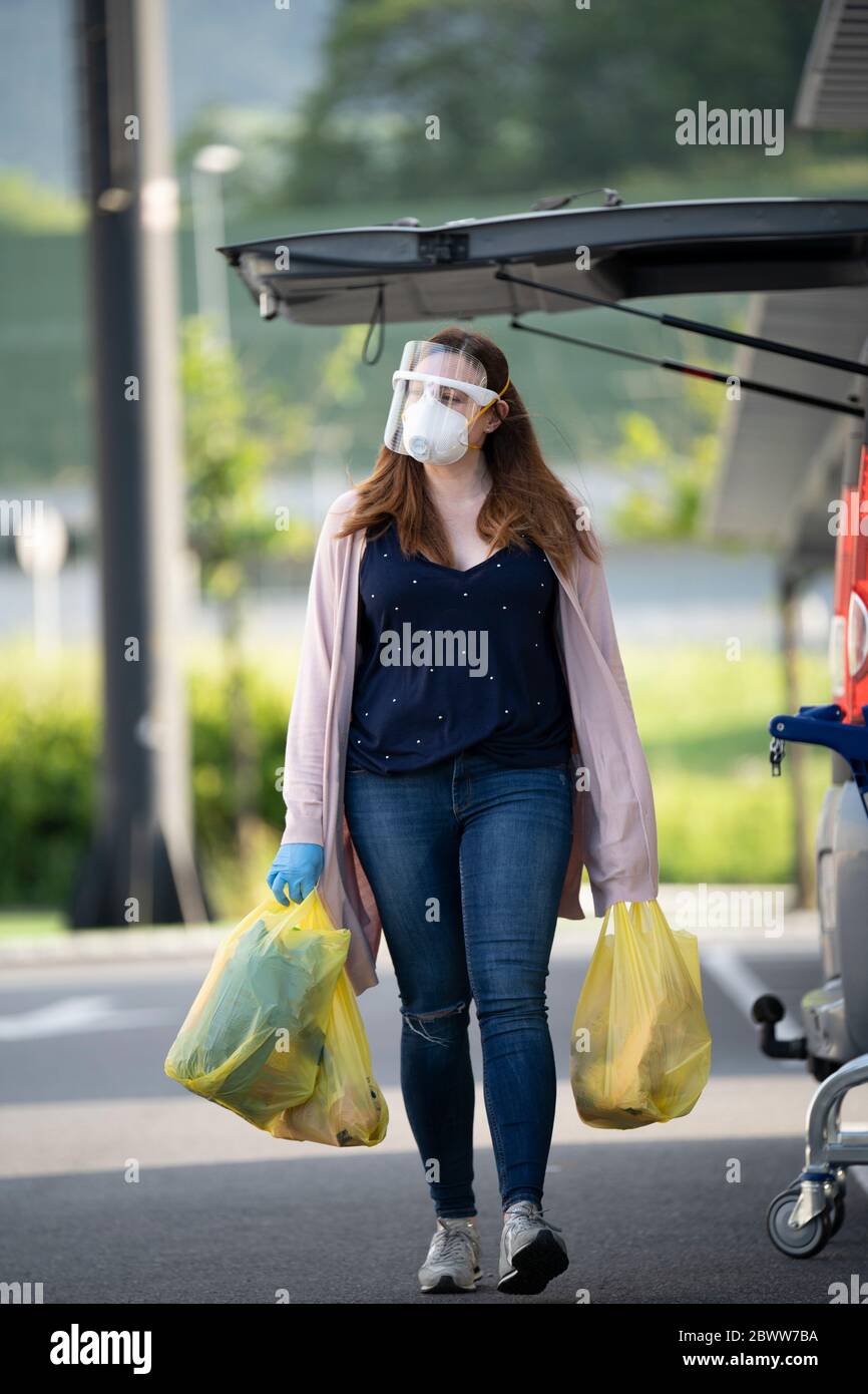 Il cliente cammina con borse di plastica nel parcheggio del supermercato Foto Stock