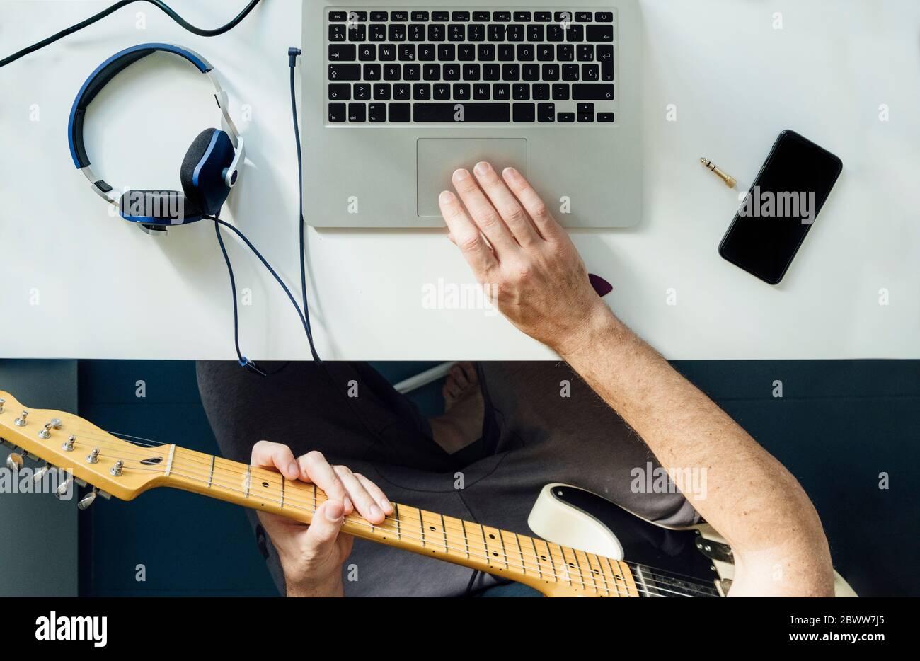 Vista in alto dell'uomo che impara a suonare la chitarra online usando un laptop Foto Stock