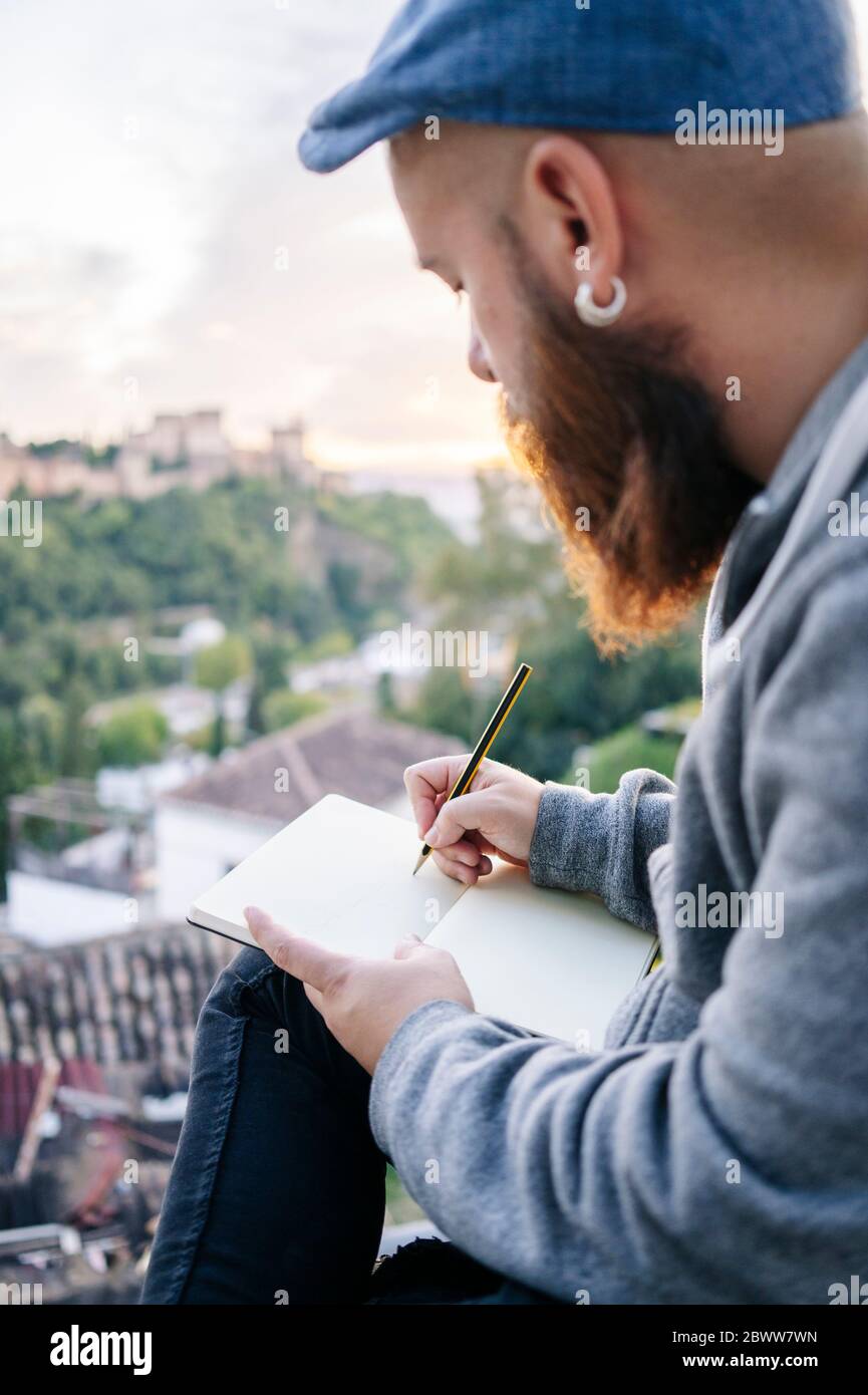 Uomo al punto di osservazione che traccia un disegno dell'Alhambra, Granada, Spagna Foto Stock