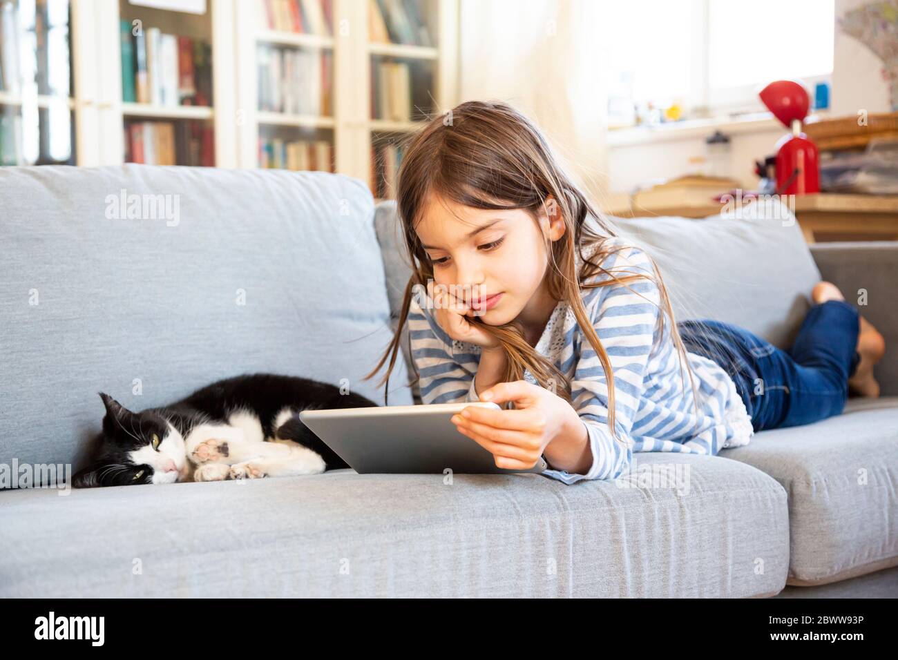 Ritratto di ragazza che si stette sul divano utilizzando un tablet digitale Foto Stock