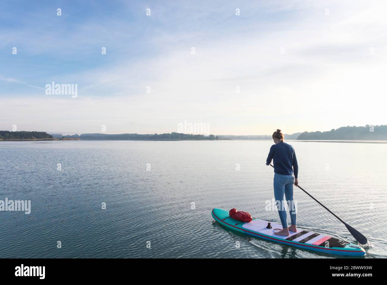 Donna in piedi su sup bordo al mattino su un lago Foto Stock