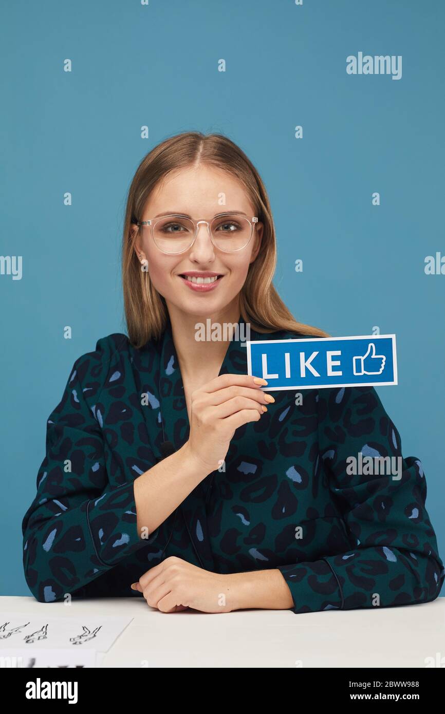 Ritratto di giovane bella donna che tiene il cartello e sorridendo alla macchina fotografica contro lo sfondo blu Foto Stock