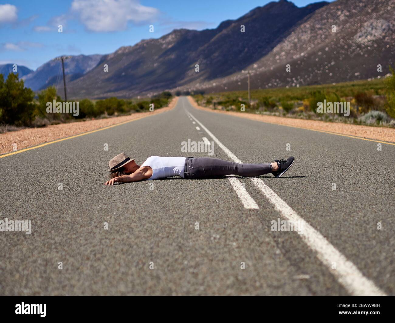 Donna che si trova nel mezzo di una strada circondata da montagne, Swellendam zona, Sudafrica Foto Stock