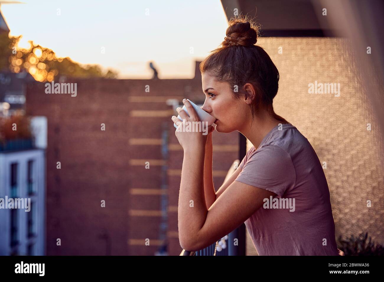 Giovane donna sul balcone che beve il tè la sera Foto Stock