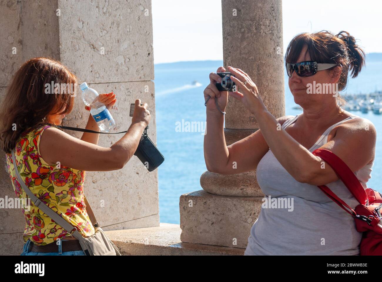Due donne turisti che scattano foto in direzioni opposte Foto Stock