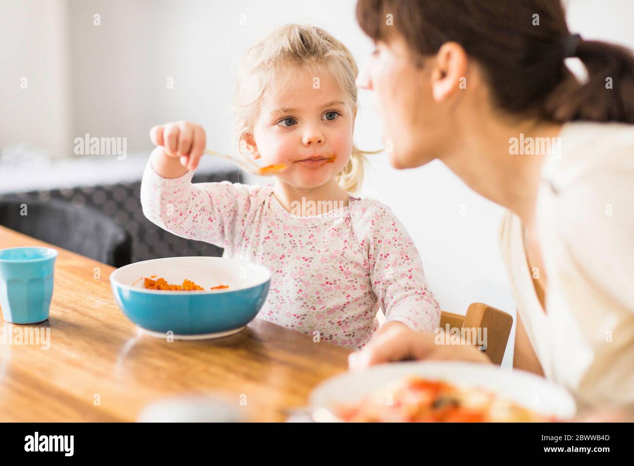 Figlia che alimenta la madre con il cucchiaio a casa Foto Stock