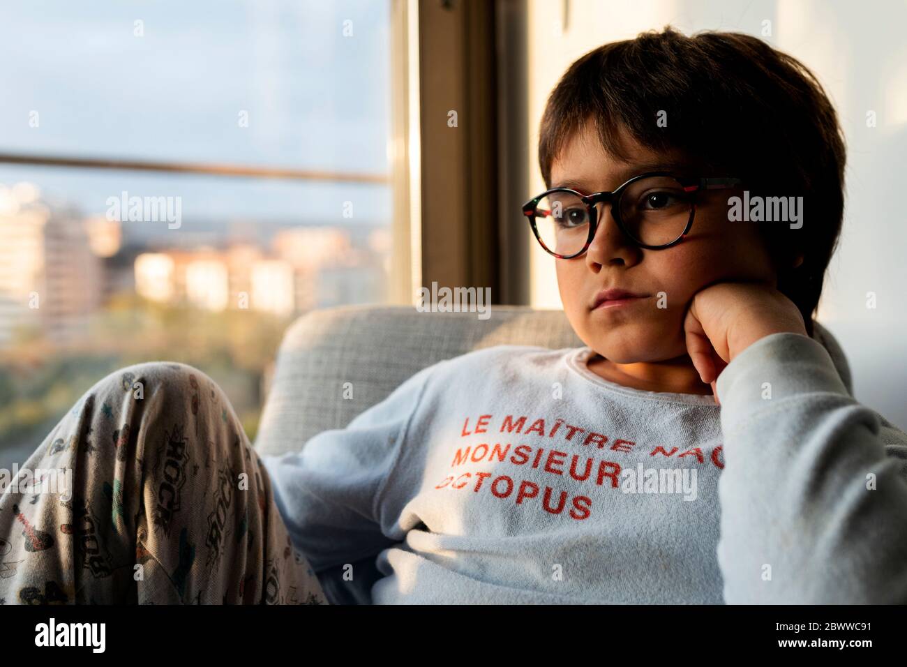 Ritratto di ragazzo annoiato seduto su poltrona a casa Foto Stock