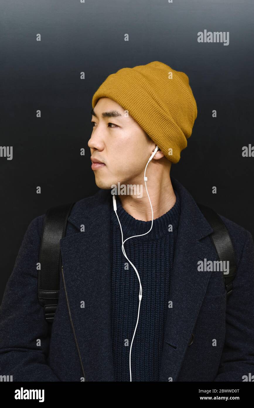 Ritratto di un uomo elegante con cappello giallo e auricolari Foto Stock