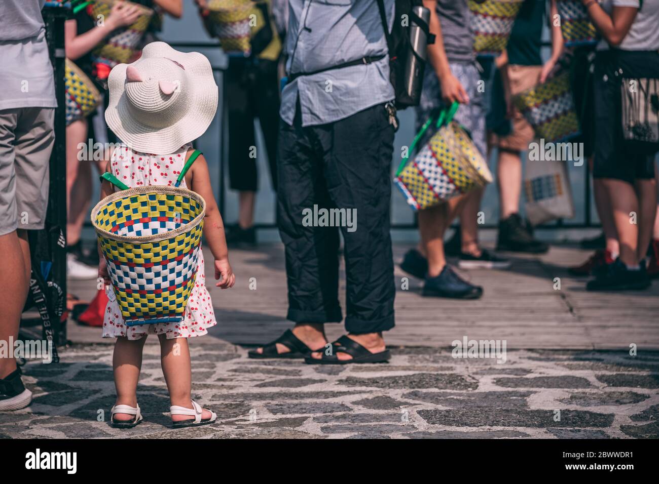 Yangshuo, Cina - Agosto 2019 : cute piccola ragazza cinese che indossa un grande cesto di vimini sulla sua parte posteriore mentre cammina su una strada e lo shopping con i suoi genitori Foto Stock