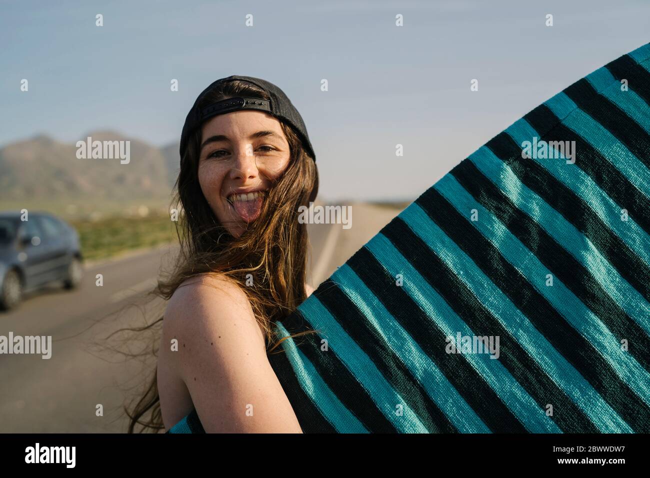 Ritratto di giovane donna con tavola da surf che si stacca la lingua, Almeria, Spagna Foto Stock