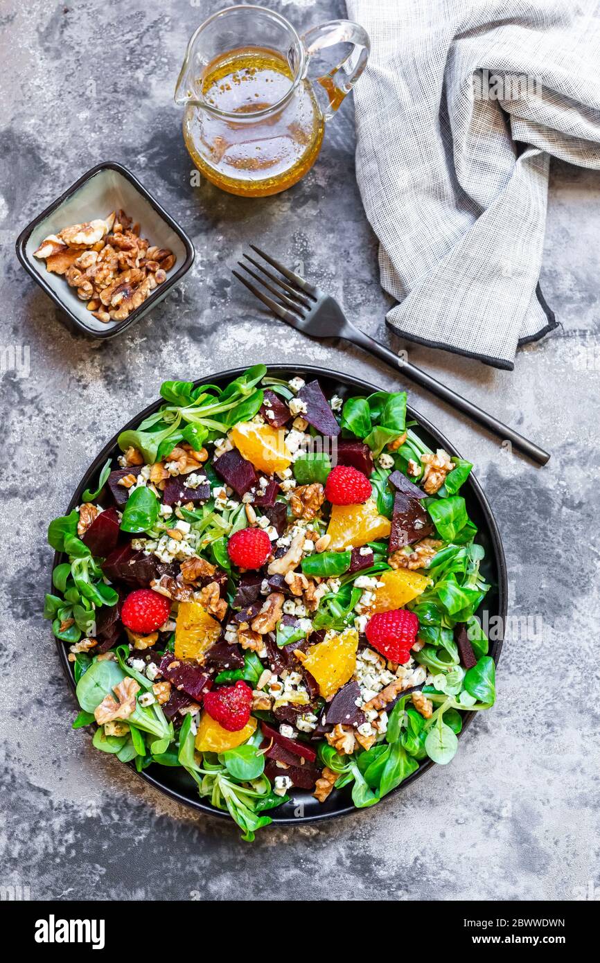 Piatto di insalata mista con formaggio feta, barbabietole, noci, insalata di mais, lamponi, arance e pinoli Foto Stock