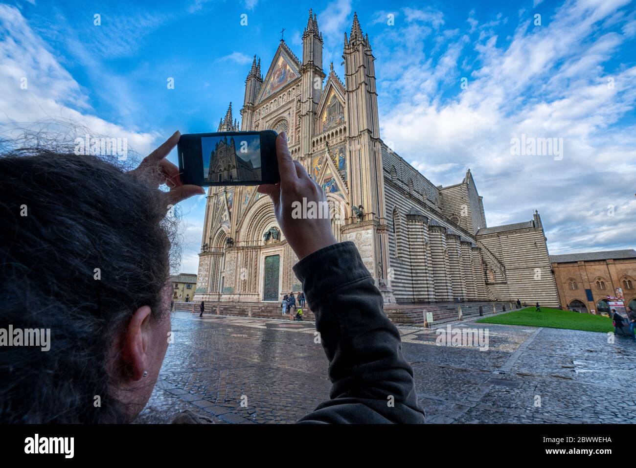 Italia, Umbria, Orvieto, vista a spalla di una donna che fotografa la Cattedrale di Orvieto Foto Stock