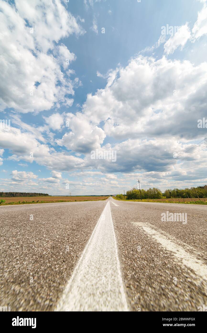 Infinita strada di campagna all'orizzonte sotto il cielo nuvoloso. Vista in prima persona Foto Stock