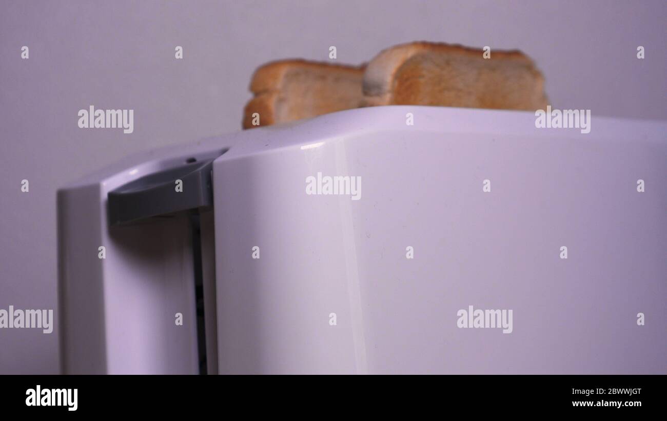 In cucina, un ragazzo (ragazza) tira fuori il cibo dal frigorifero e prepara la colazione accanto al tostapane, tostapane pronti tostapane sono tirati fuori. Foto Stock