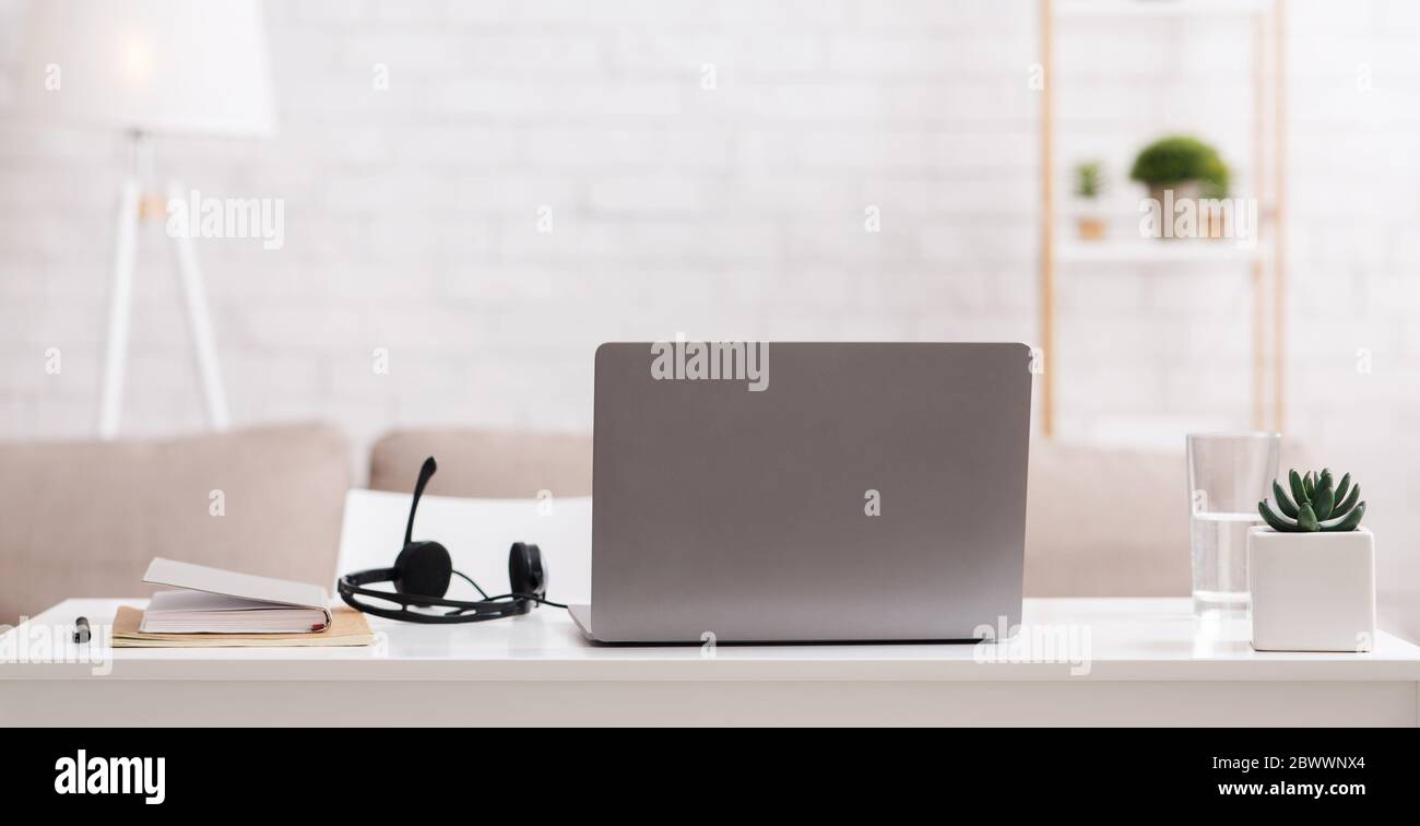Consulenza online e lavoro remoto da casa. Sul tavolo sono presenti notebook, blocco note e cuffie con microfono Foto Stock