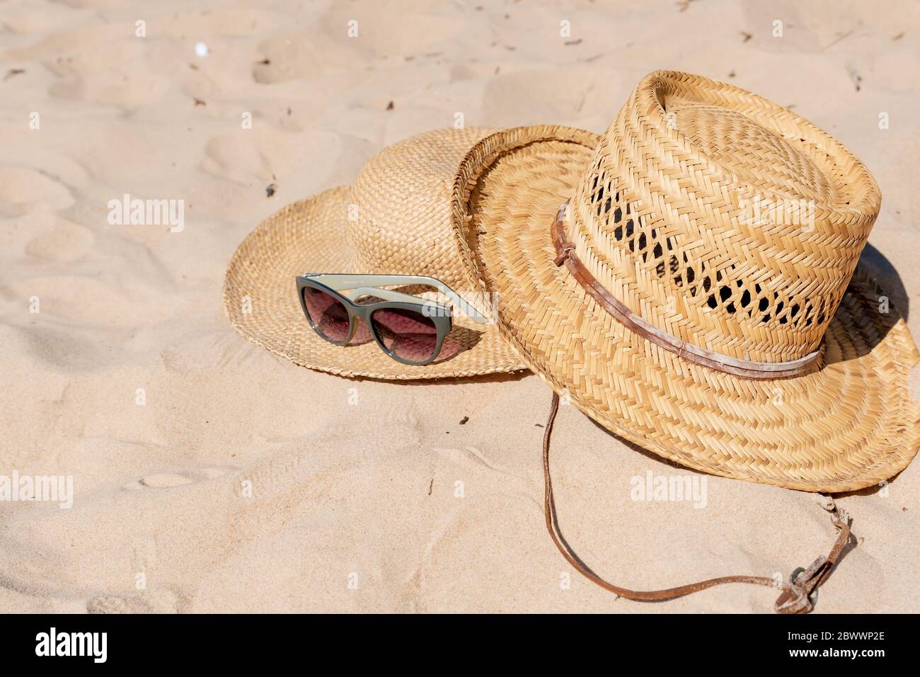 Vista sulla spiaggia di sabbia con cappelli estivi e occhiali da sole. Layout di annunci pubblicitari o packaging vuoto. Foto Stock