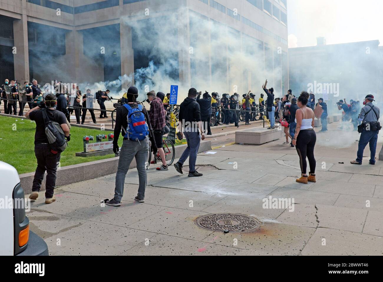 Il gas lacrimogeno riempie l'aria di fronte al Cleveland Justice Center, dove i manifestanti contro l'uccisione di George Floyd si sono riuniti per dimostrare. Migliaia di manifestanti sono scesi sul Cleveland Justice Center, sede della Cleveland Police Headquarters, nel centro di Cleveland, Ohio, USA, dove la polizia ha utilizzato gas lacrimogeni e spray al pepe per cercare di controllare la folla. Il centro di Cleveland era pieno di manifestanti e come il giorno progredisce così ha fatto il saccheggio, il vandalismo e l'illegalità il 30 maggio 2020. Foto Stock