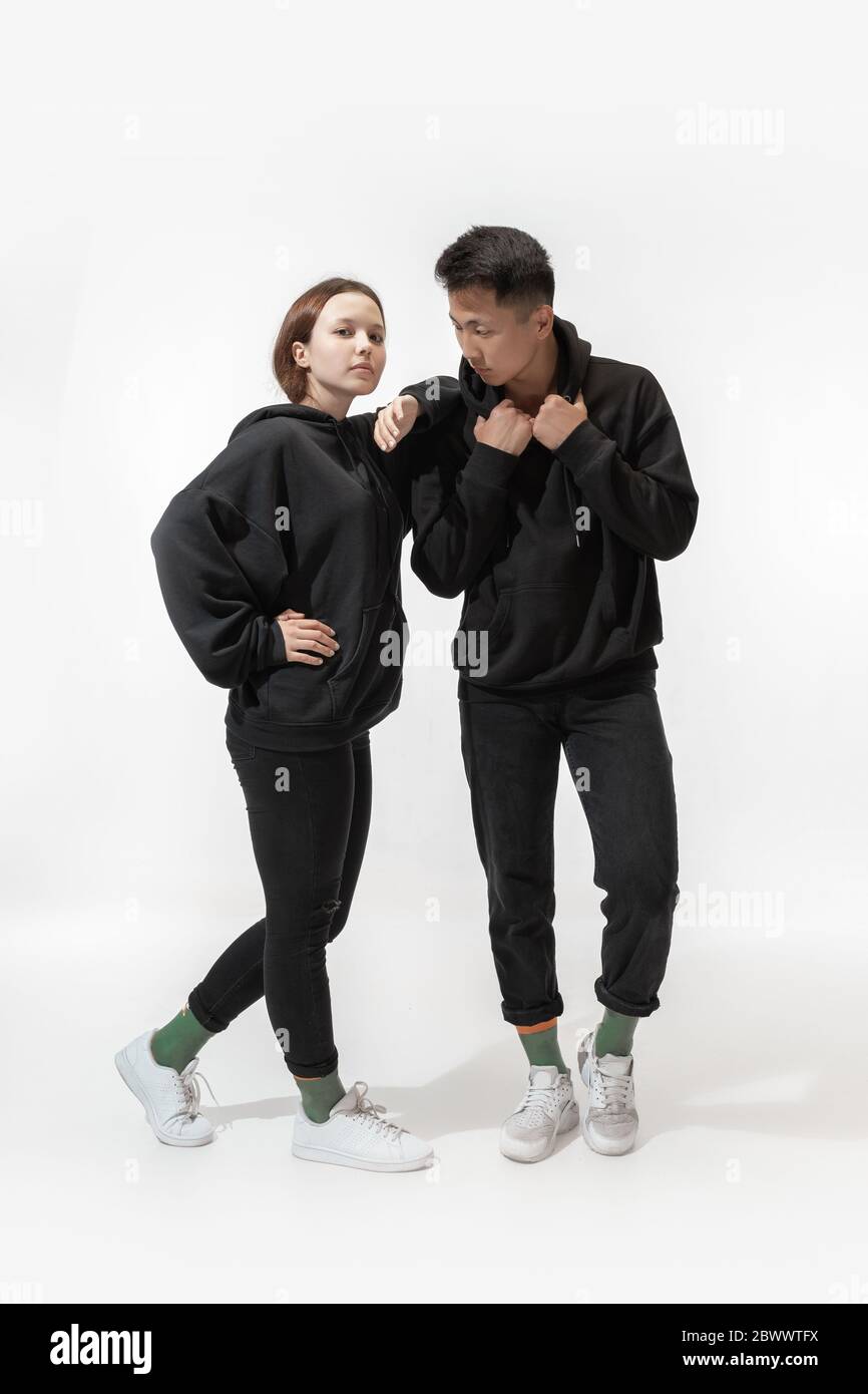 Amico. Coppia alla moda isolata su sfondo bianco. Donna e uomo alla moda che posano in abiti minimal di base, adatti anche a entrambi. Concetto di uguaglianza, inclusivo. Foto Stock