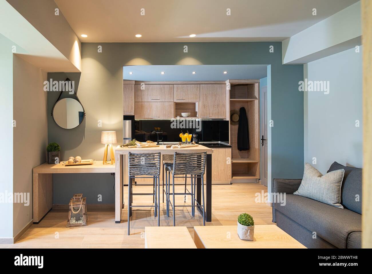 Interni moderni in grigio e legno di un piccolo monolocale. Vista frontale della camera dell'hotel con cucina, soggiorno, camera da letto in camera singola Foto Stock