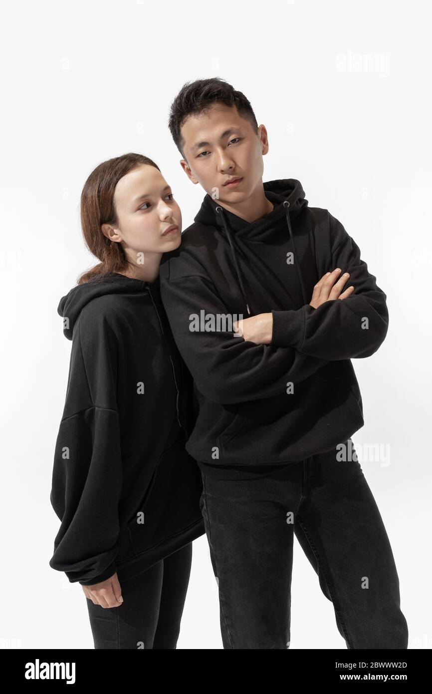 Moda. Coppia alla moda isolata su sfondo bianco. Donna e uomo alla moda che posano in abiti minimal di base, adatti anche a entrambi. Concetto di uguaglianza, inclusivo. Foto Stock