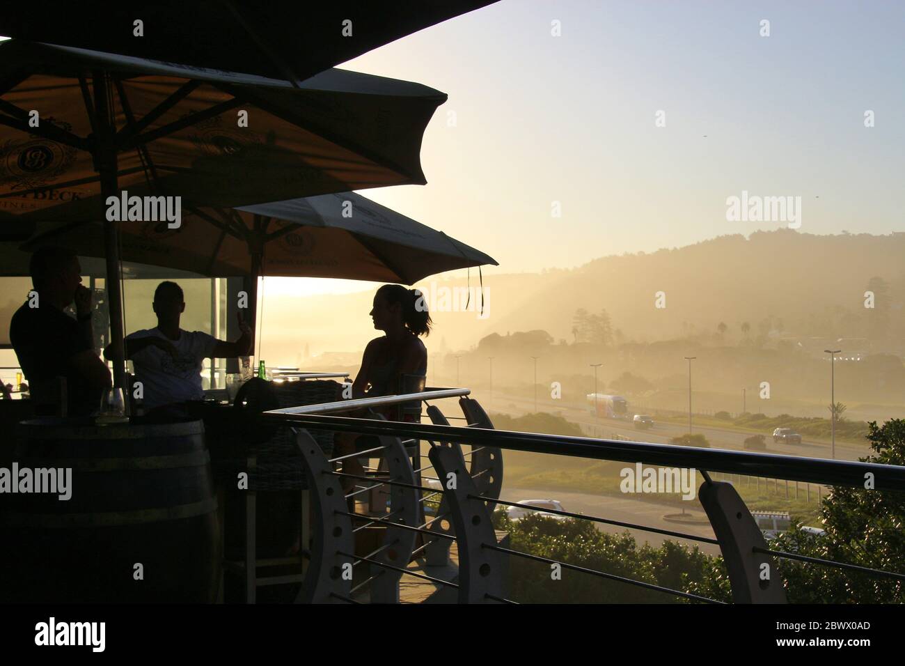Wilderness, Sudafrica, Africa - Febbraio 2020: Terrazza di un ristorante sulla spiaggia e sagome degli ospiti in bella luce tramonto. Foto Stock