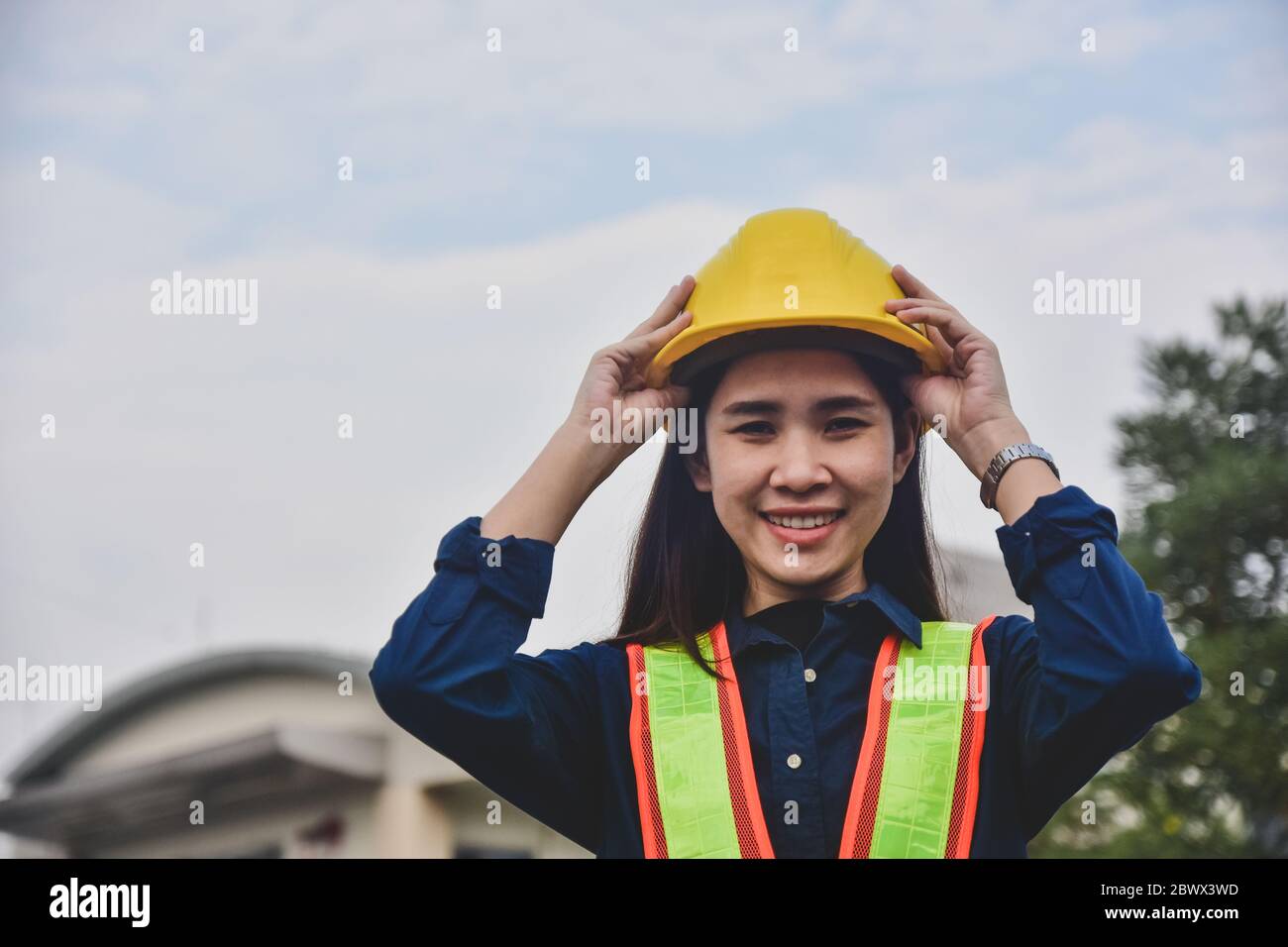 Donne Ingegneria toccare su elmetto di sicurezza in piedi luogo di lavoro esterno Foto Stock