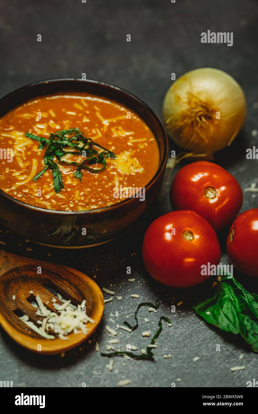 Zuppa rustica di pomodoro basilico cipolla pomodoro cucchiaio di legno di formaggio fuso caldo Foto Stock