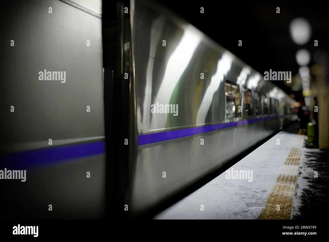 Piattaforma della metropolitana sfocata a Sapporo nella notte invernale con neve bianca sul terreno della piattaforma. Foto Stock