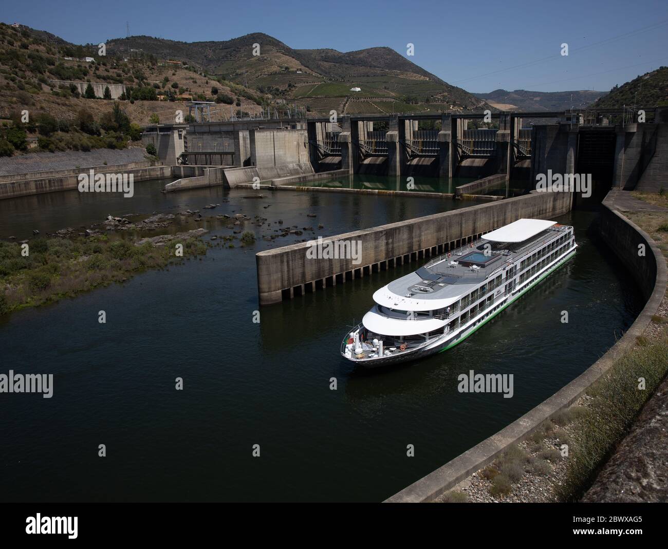 Nave da crociera fluviale che lascia la diga di Bagauste sul fiume Douro nel Portogallo settentrionale Foto Stock