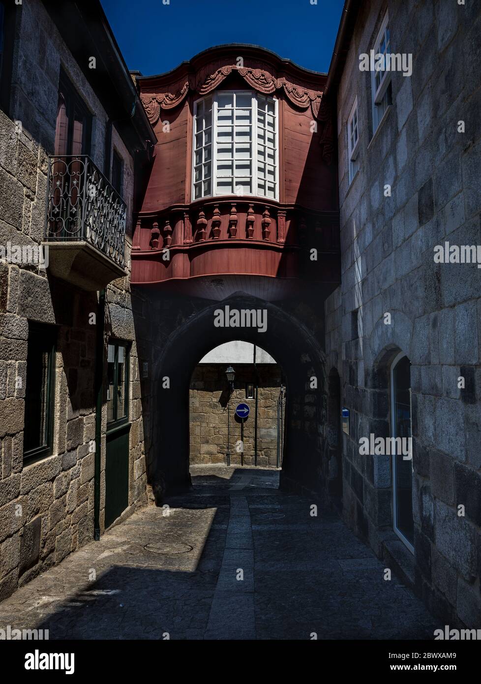 Vecchia strada stretta con alte case medievali terrazzate e arco nella storica città di Lomego Portogallo Foto Stock