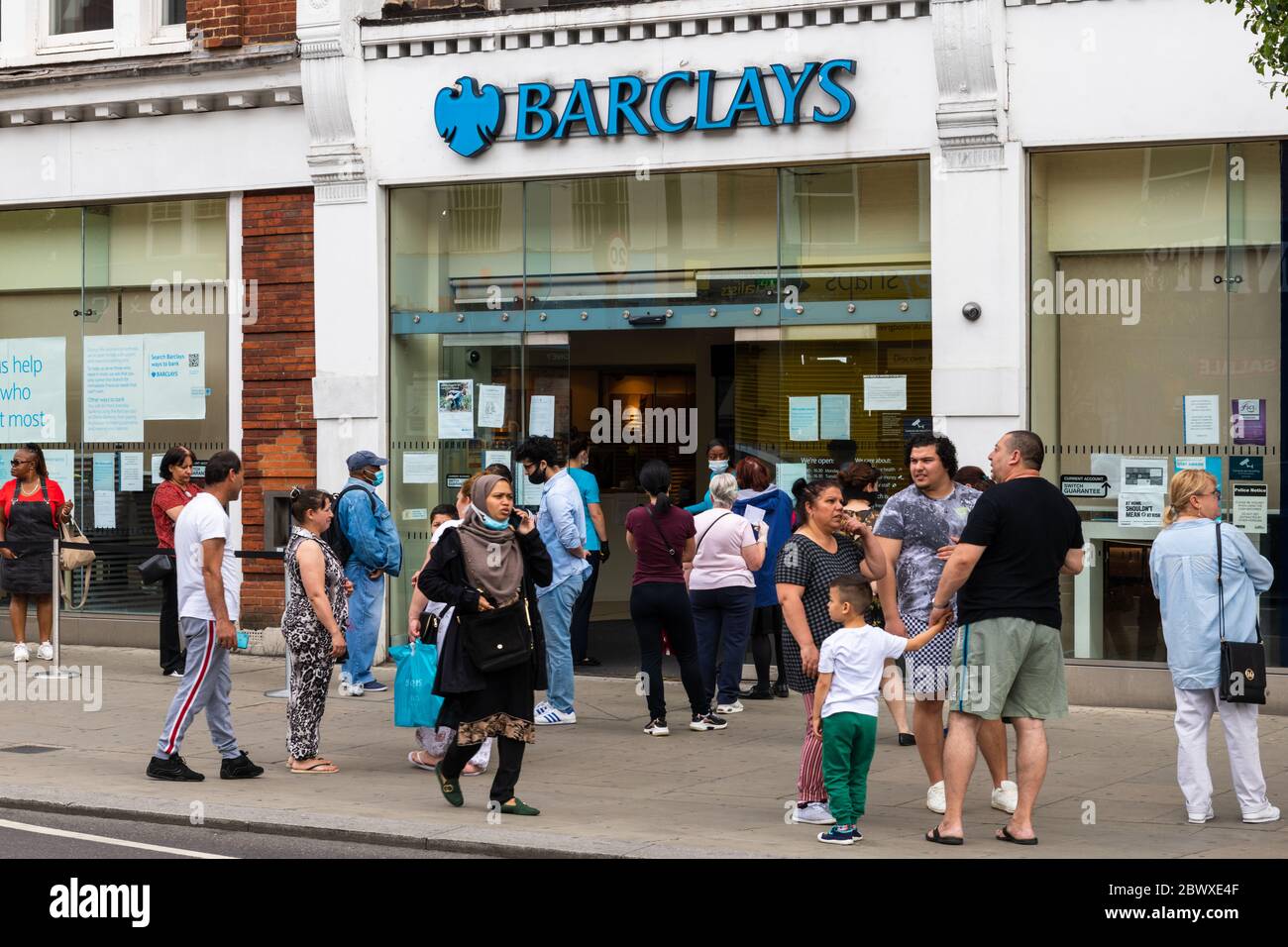 Una folla di persone fuori da una filiale di Barclays Bank. Le restrizioni di allontanamento sociale hanno causato lunghe code soprattutto per le banche. Foto Stock