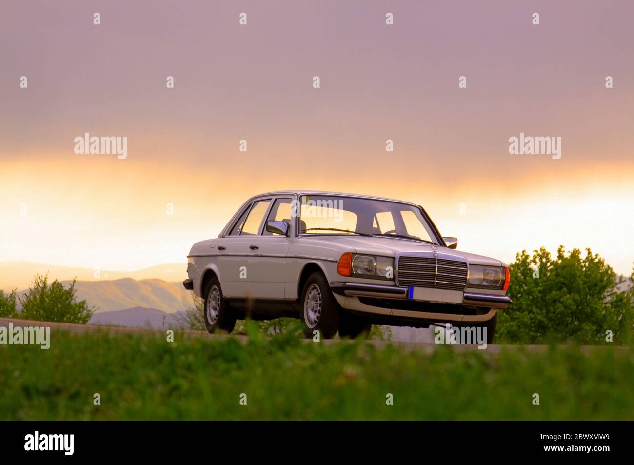 CLUJ-NAPOCA, ROMANIA - 5 agosto 2011: Editoriale illustrativo - Classic Mercedes-Benz W 123 berlina bianca auto all'aperto in natura al tramonto Foto Stock