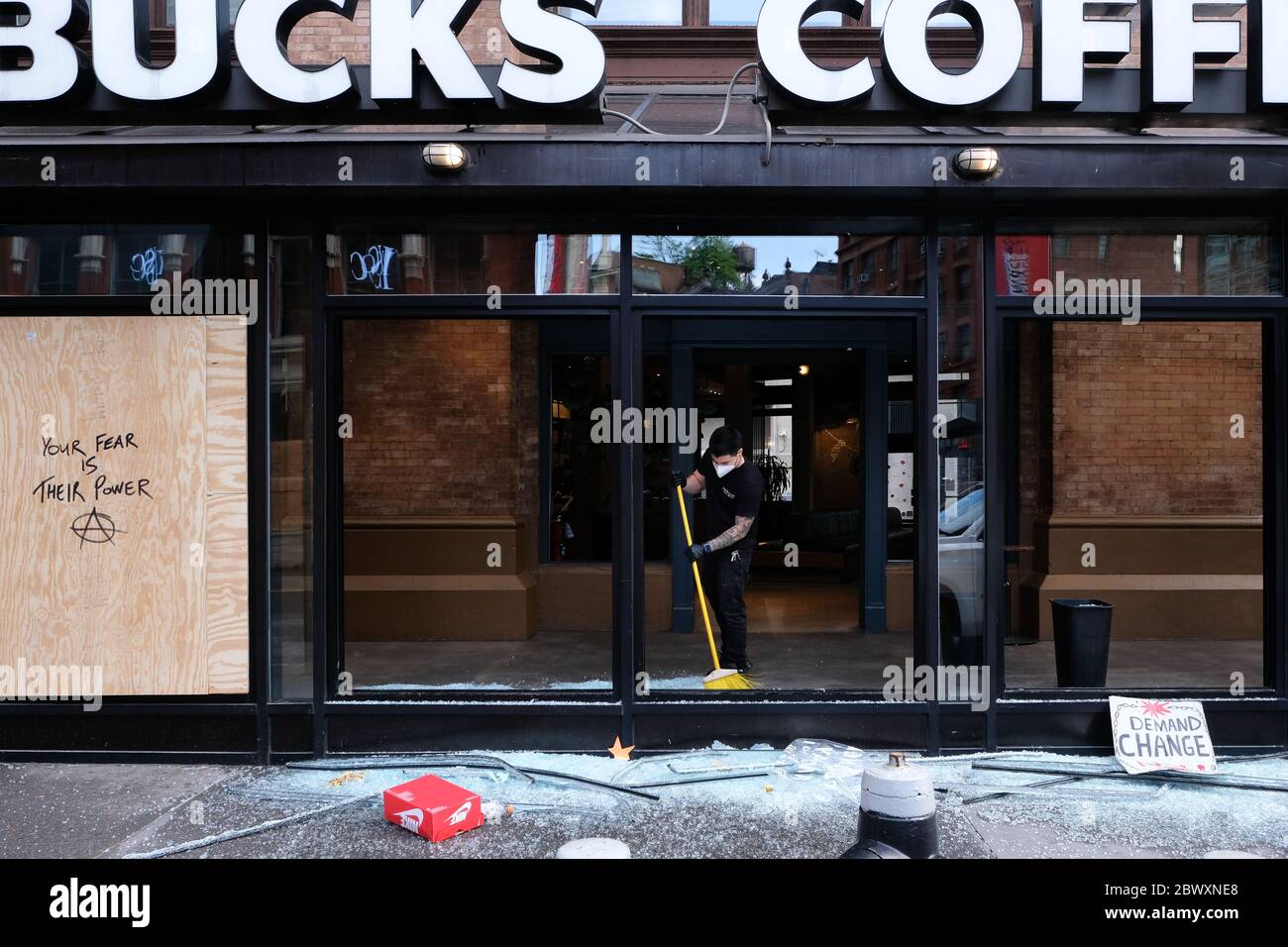 Un uomo pulisce il vetro rotto allo Starbucks su Astor Place a Manhattan la mattina dopo l'ottavo giorno delle proteste di George Floyd a New York City. Foto Stock
