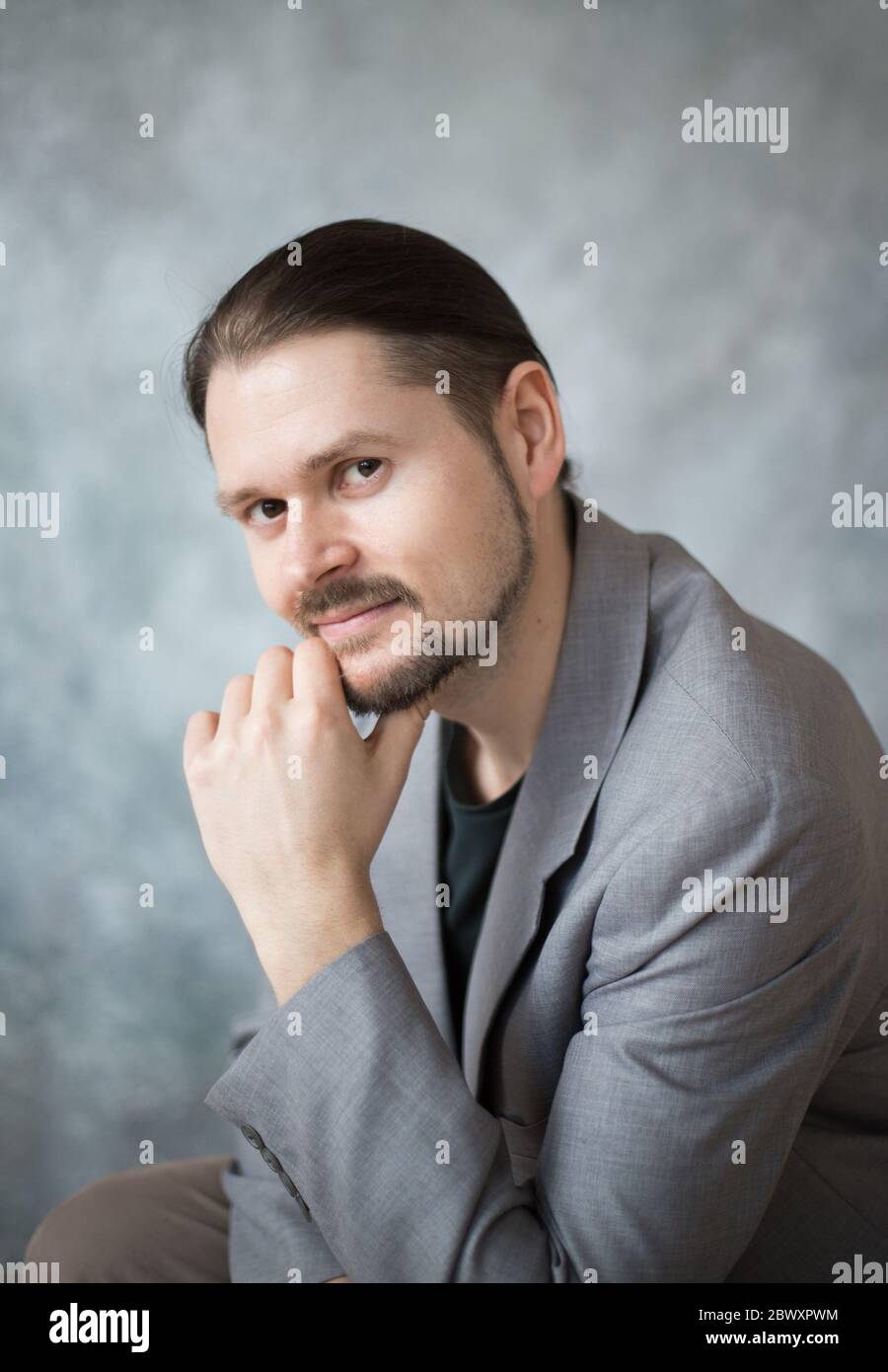 Ritratto di un giovane in giacca da lavoro su sfondo grigio nello studio. Foto Stock