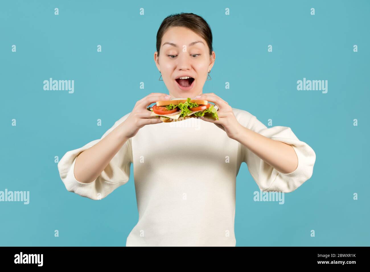 Una giovane donna manda un panino in bocca Foto Stock