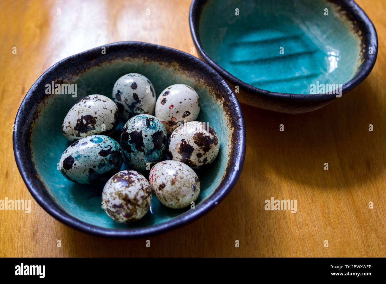 Le uova di pasqua macchiate di turchese e verde in una bella ciotola di ceramica su un tavolo di legno Foto Stock