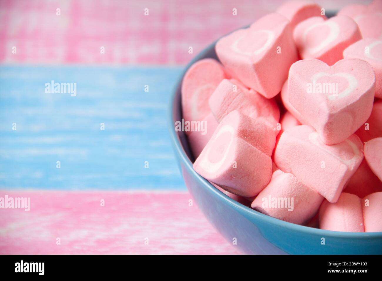 Romantici marshmallow a cuore rosa in ciotola blu Foto Stock