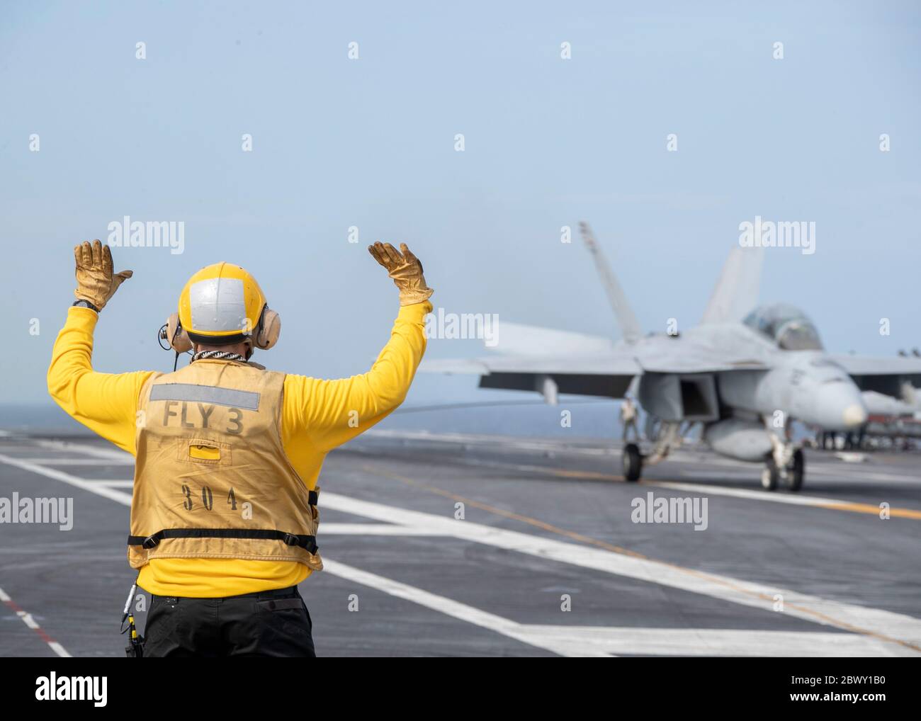 Segnali della giacca gialla della marina degli Stati Uniti alle navi che comandano ufficiali Capt. J.J. Cummings, che atterra il suo F/A-18F Super Hornet sul ponte di volo della compagnia di aerei della classe Ford USS Gerald R. Ford 15 maggio 2020 nell'Oceano Atlantico. Foto Stock
