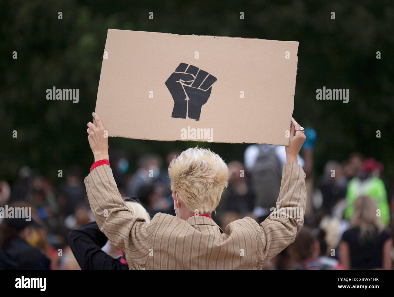 Uomo dai capelli biondi che tiene in mano un segno nero pugno fatto in casa, al Black Lives Matter UK protesta marzo. Londra, Inghilterra, Regno Unito Foto Stock