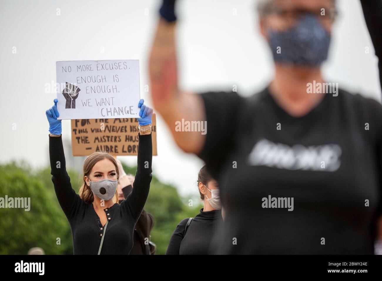 Giovane donna, indossando guanti e una maschera facciale, che tiene un segno fatto in casa durante la marcia di protesta Black Lives Matter UK. Londra, Inghilterra, Regno Unito Foto Stock