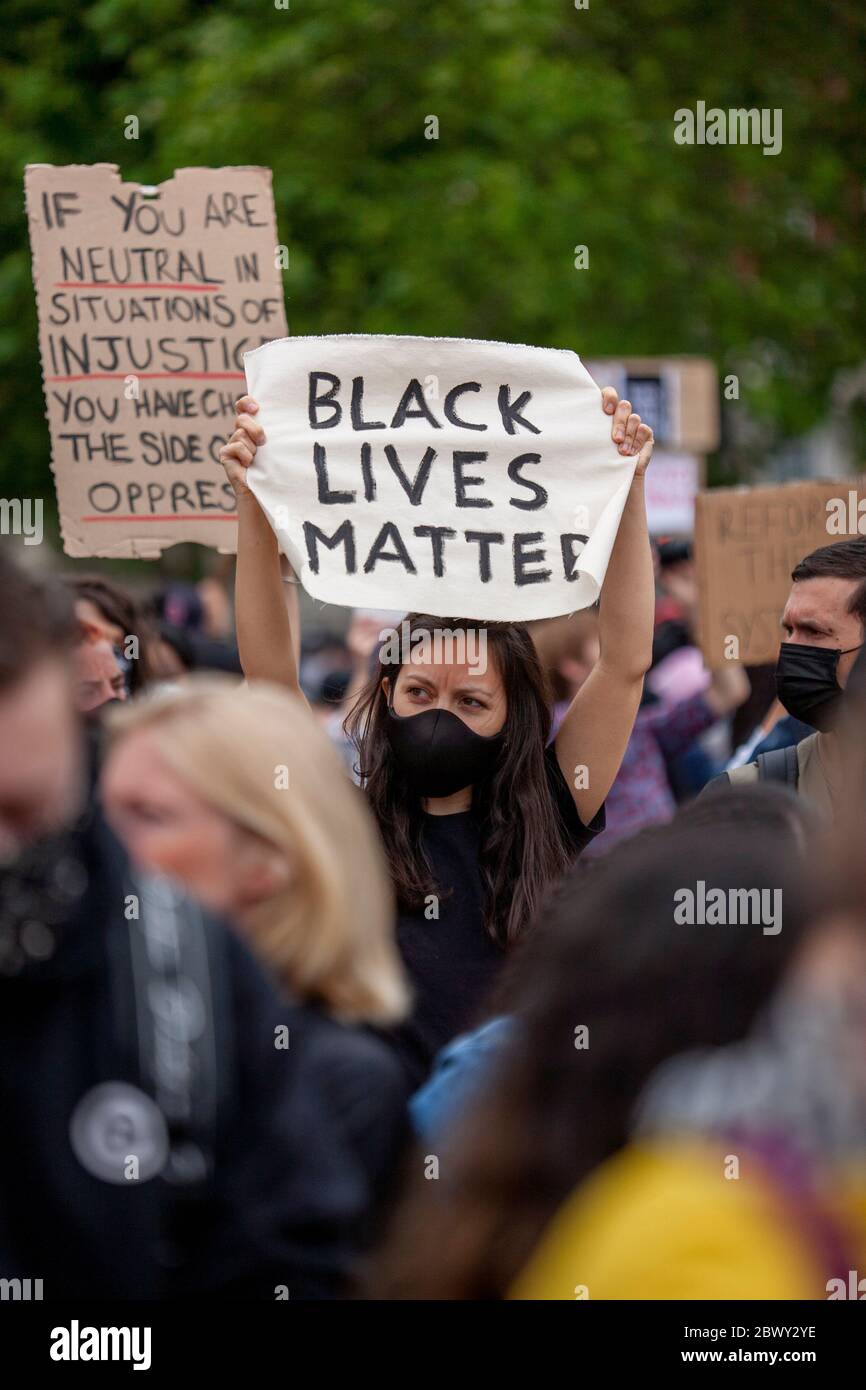 Giovane donna, indossando una maschera nera, che tiene in mano un segno 'Black Lives Matter' durante la marcia di protesta Black Lives Matter UK. Londra, Inghilterra, Regno Unito Foto Stock