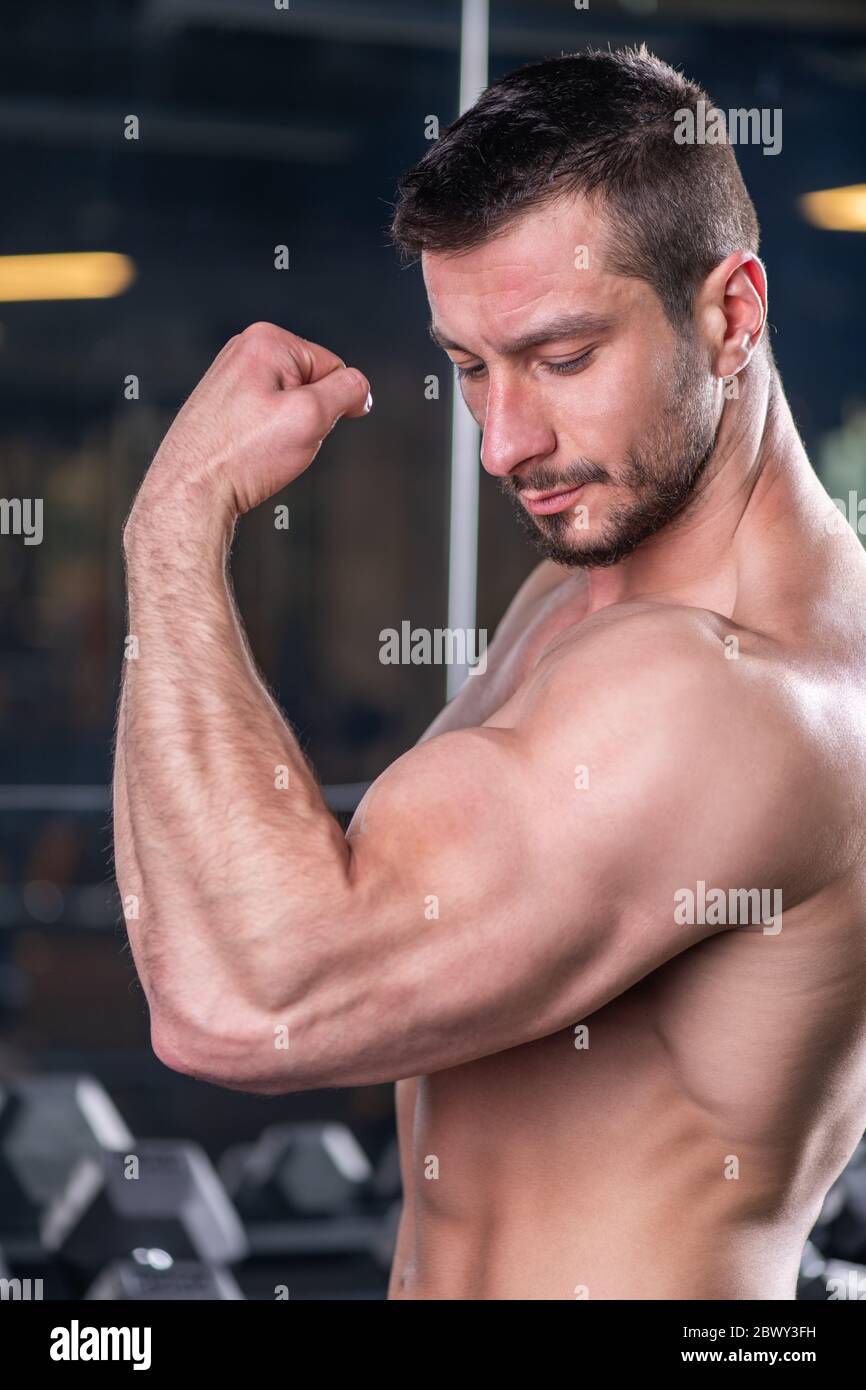 Giovane uomo sexy muscolare che posa con contrazione bicipite Foto Stock