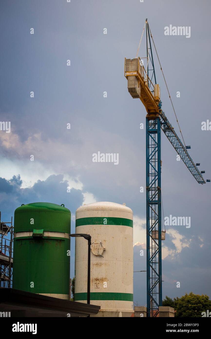 Gru a torre e silos in cemento in un cantiere con cielo blu. Scatto verticale, sfondo o sfondo dell'edificio. Foto Stock