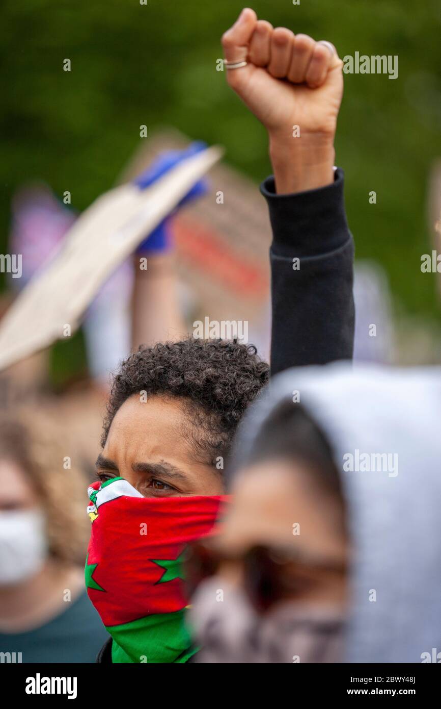 Donna, indossando una sciarpa per coprire il viso, solleva il pugno in sfida di razzismo durante la marcia di protesta del Regno Unito Black Lives Matter. Londra, Inghilterra, Regno Unito Foto Stock
