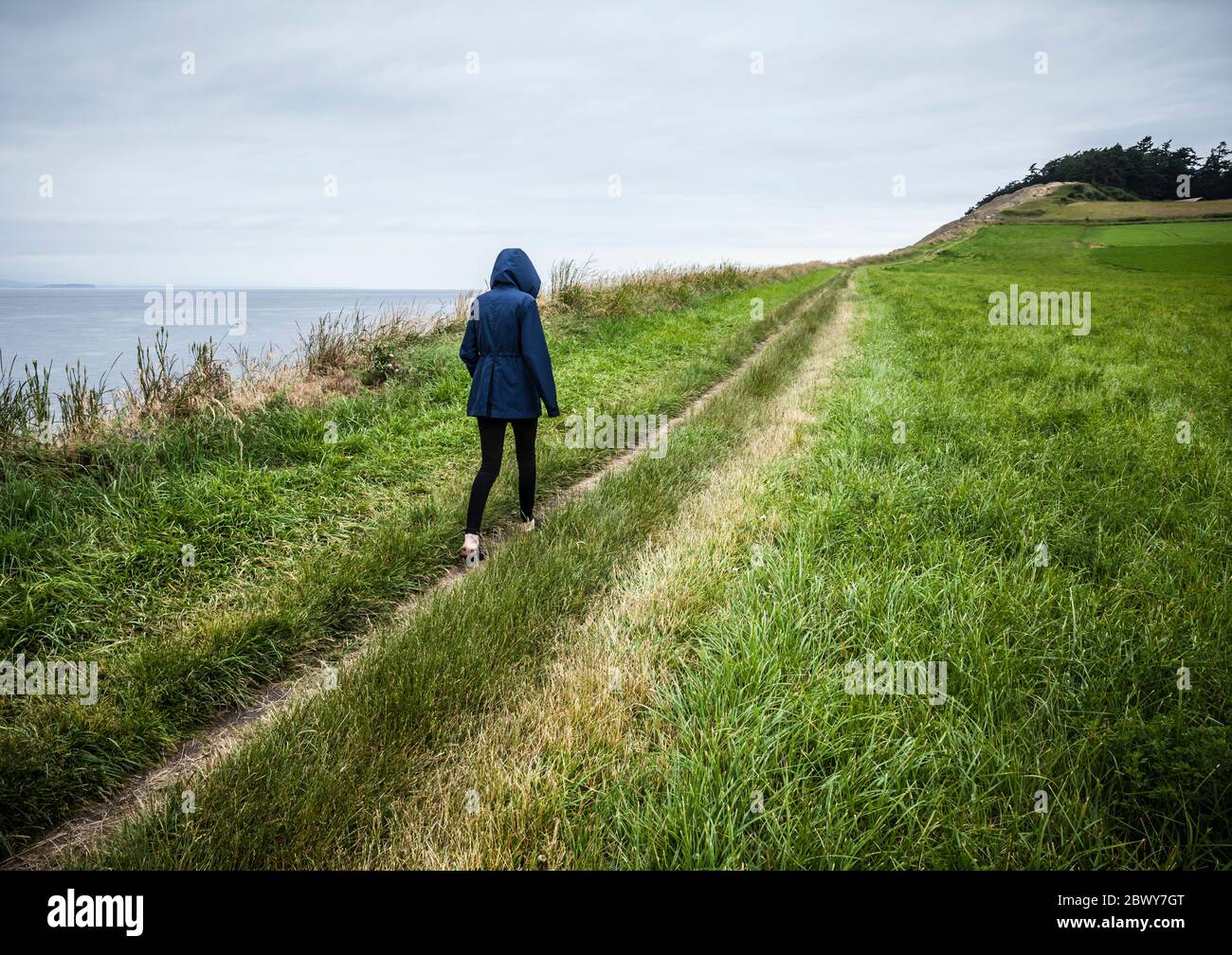 Una giovane donna che cammina lungo il sentiero per Ebeys Bluffs, Ebey's Landing National Historical Reserve, Whidbey Island, Washington, USA. Foto Stock