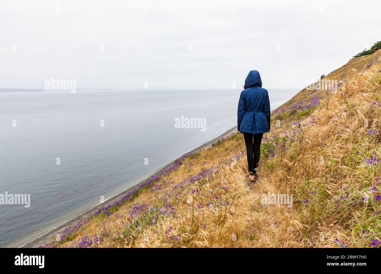 Una figura con cappuccio/giovane donna sola su Ebby Bluff, Ebey's Landing National Historical Reserve, Whidbey Island, Washington, USA. Foto Stock
