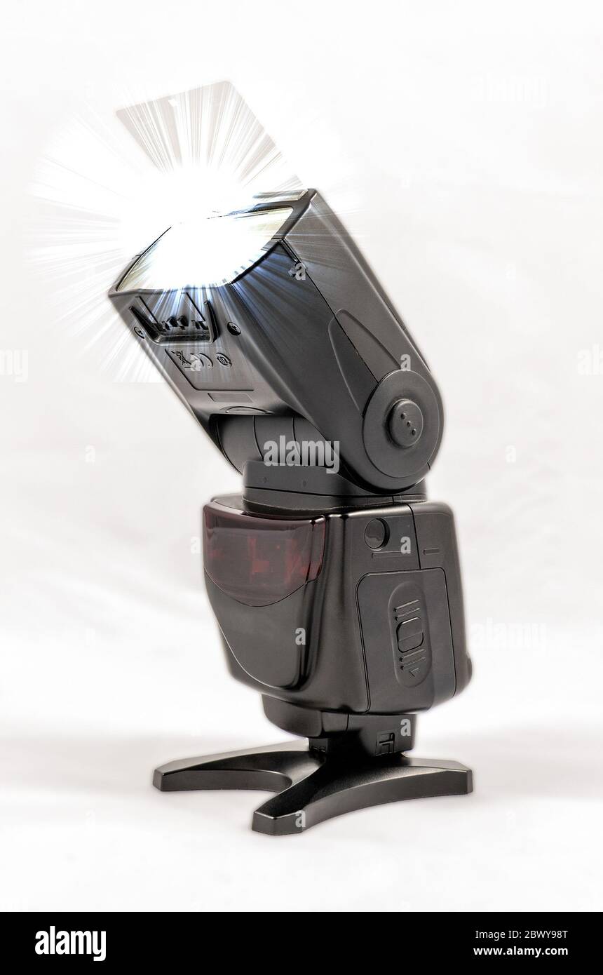 Vista obliqua di un'unità flash esterna nera senza marchio per fotocamere DSLR con scheda di rimbalzo estesa durante le riprese Foto Stock