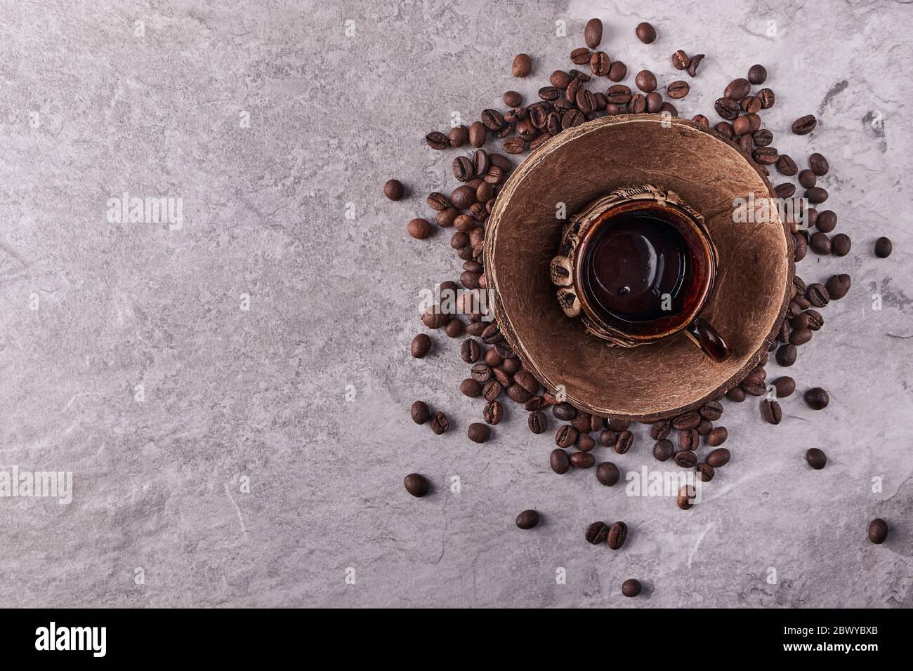 Vista dall'alto dei chicchi di caffè tostati in conchiglia di cocco su rustico sfondo di legno, fotografia di vita con chicchi di caffè tostati Foto Stock
