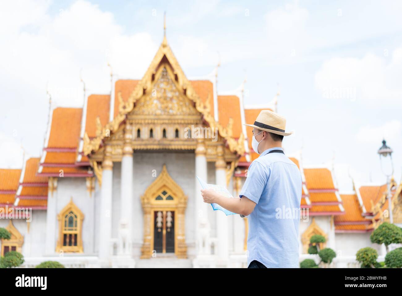 Uomo asiatico turisti felici di viaggiare indossando maschera per proteggere da Covid-19 sulle sue vacanze e lui guardando la mappa di viaggio a Tempio a Bangkok, Thailandia Foto Stock
