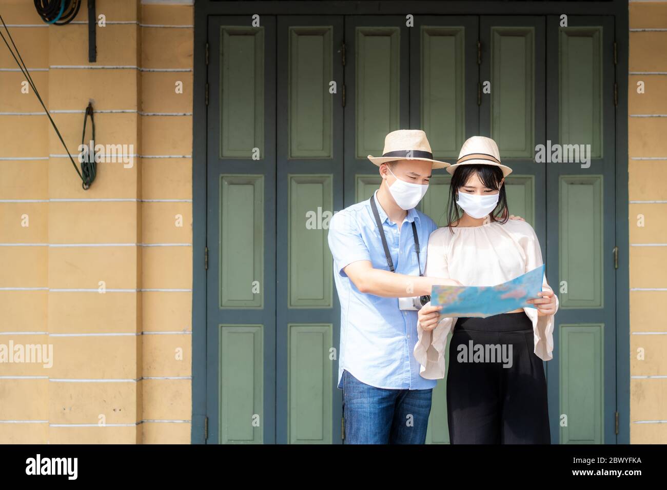 Coppia asiatica turisti felici di viaggiare indossare maschera per proteggere da Covid-19 su loro vacanze e tenendo mappa di viaggio nella città vecchia di Bangkok, Thailandia Foto Stock